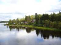 N�gra sommarstugor nedstr�ms landsv�gsbron l�ngs h�ger �lvstrand.